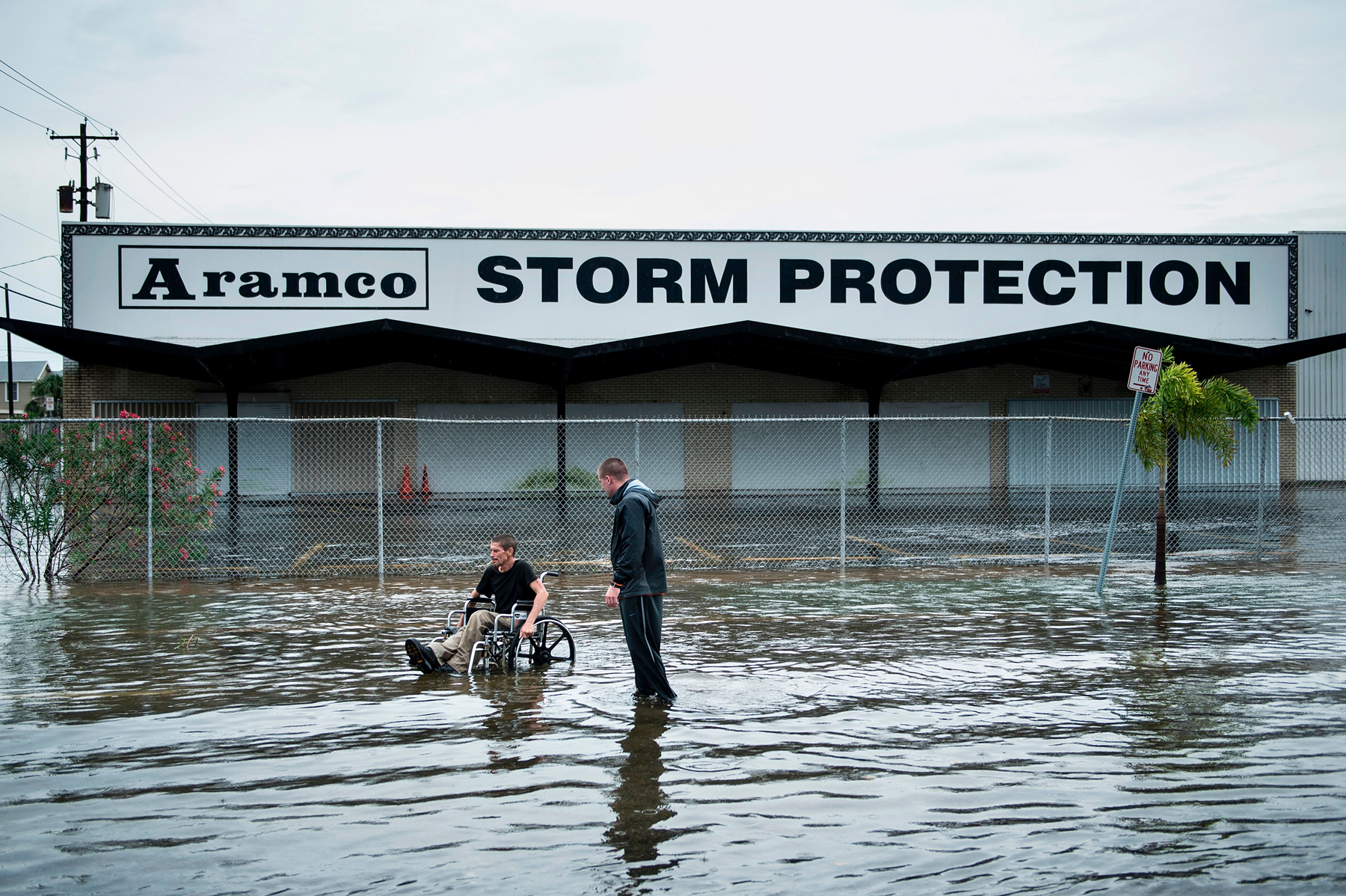 Photo, man in wheelchair and man walking in hurricane flood waters