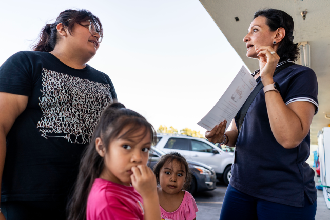 Photo, two women talk about health care over two children