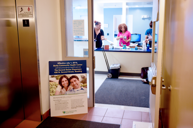 Three health care workers at the front desk behind the open door Berks Community Health Center