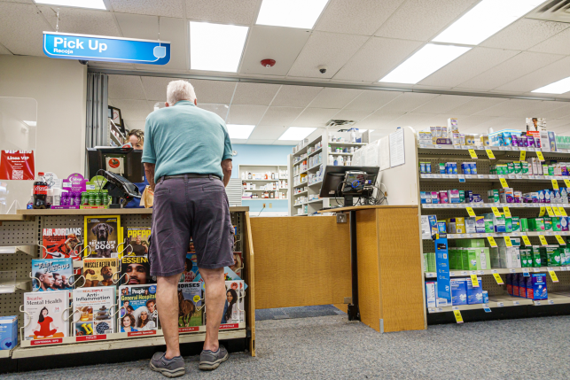 Elderly man picking up prescription at drug store counter