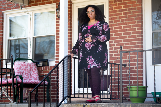 Pregnant woman standing outside front entrance of her home