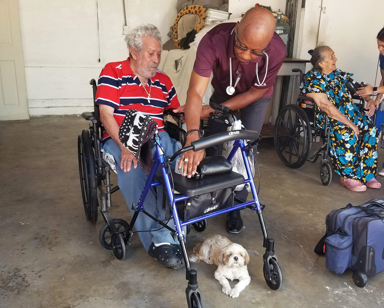 Nurse helps elderly patient in wheelchair get into walker