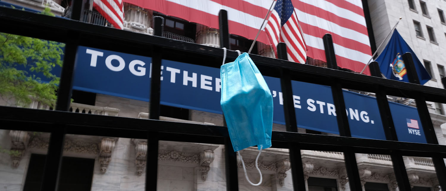 Health Care in 2020 Year in Review face mask hanging in front of the New York Stock Exchange