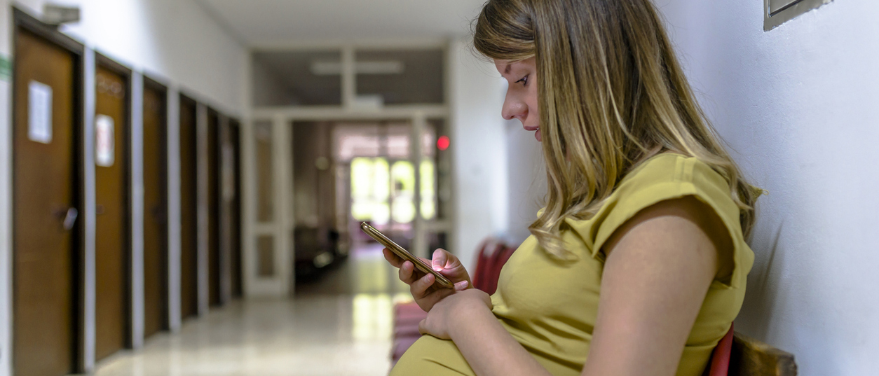 Low-income patient with cell phone in hospital waiting room