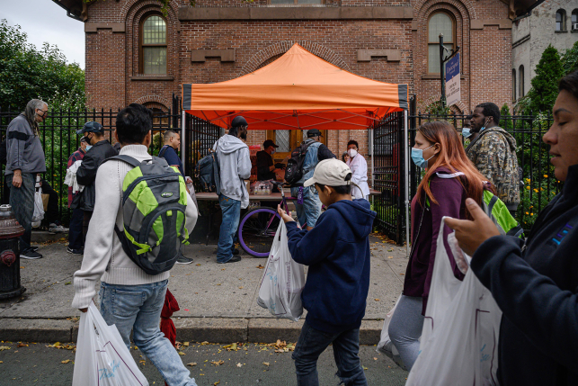 Photo, People standing in line with bags of food at soup kitchen