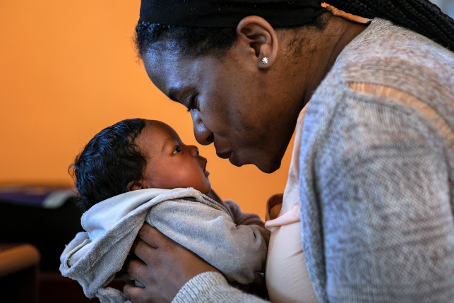Mother leans to kiss infant son's nose