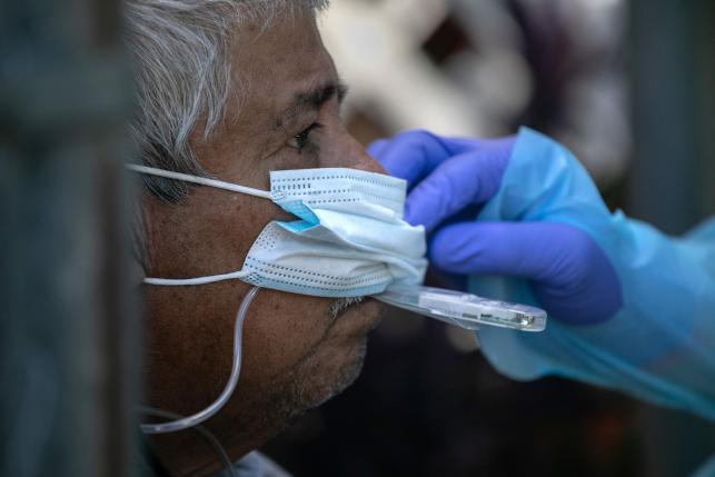 Latinx/Hispanic man getting his temperature taken by a health worker