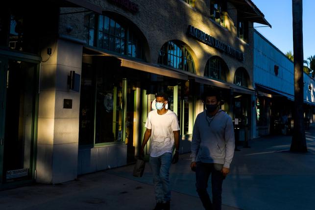 People wear face masks as they walk at a shopping district in Miami Beach, Florida.