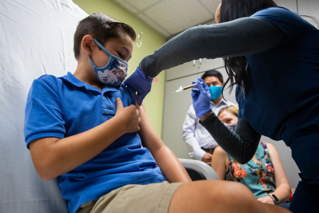 Child receiving vaccine from gloved health care provider