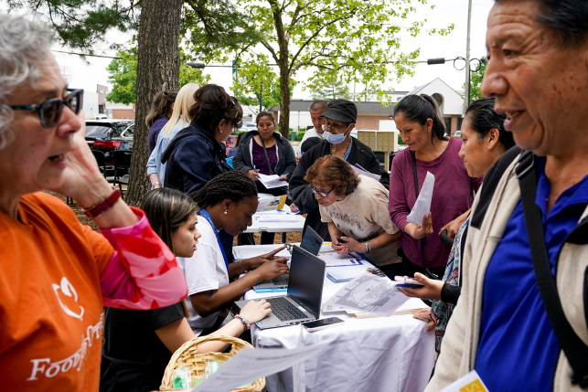 Photo, people talk on either side of a table with laptops