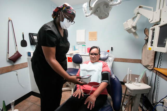 Dental assistant helps client in chair