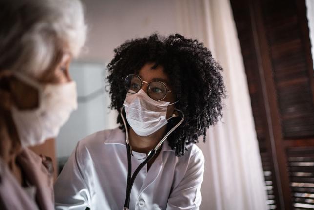 Doctor wearing a surgical mask speaks to a patient