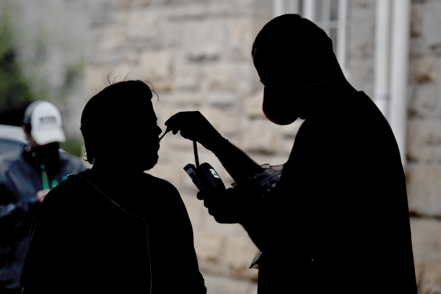 Nurse practitioner Daniel Lucas-Neel II checks the temperature of a man who asked to be screened at a pop-up coronavirus testing site run by a free clinic in Charleston, West Virginia.