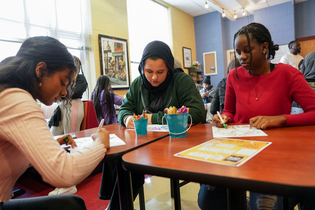 Photo, three students sitting at table with markers