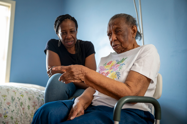 Woman smiles at her mother in a wheelchair