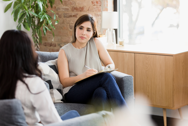 Woman talks with clipboard on couch
