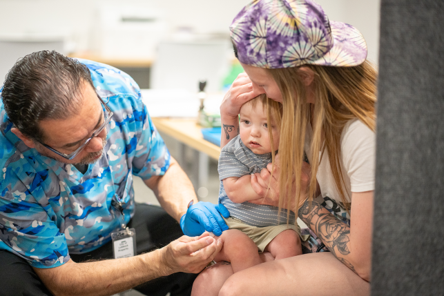 Mom holds baby who is receiving vaccination injection.