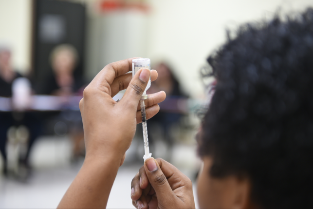 Patient educator holds syringe up to examine it