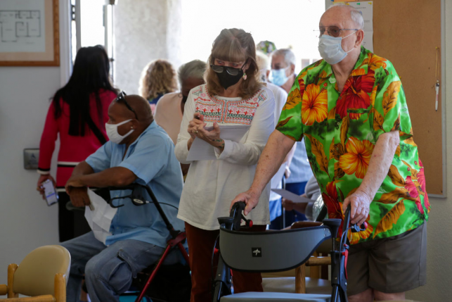 Elderly man and daughter wait in line with walker