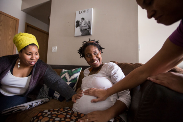 Two doulas examine pregnant patient at her home
