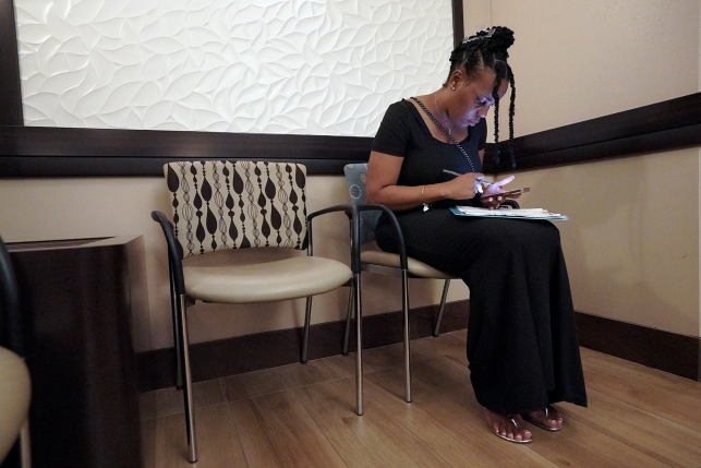 Photo, Woman filling out paperwork in waiting room chair