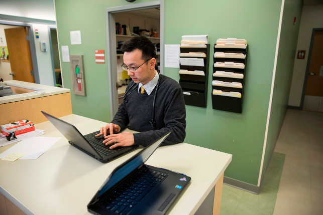 Doctor looks at patient records on laptop