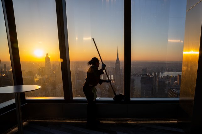 Photo, silhouette of woman pushing mop in front of NYC skyline