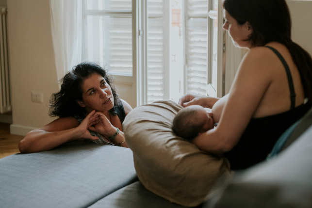 Midwife providing home breastfeeding assistance to a mother with her newborn