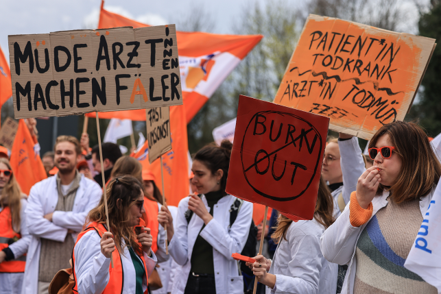 Doctors hold signs protesting in street