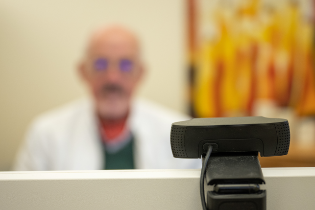 Doctor sits blurrily behind video monitor on top of computer