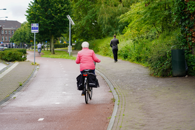 Older woman cycles on a well-maintained bike path