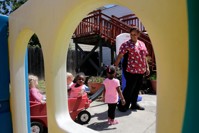 Daycare worker playing outdoors with toddlers