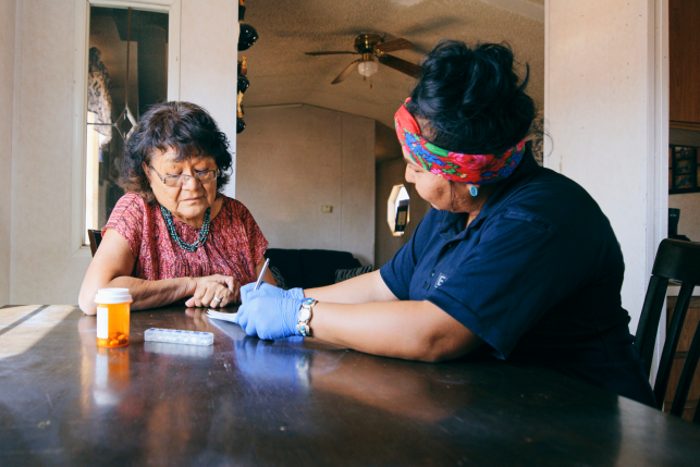 An Indigenous Navajo senior aged woman, receiving healthcare assistance in her home.