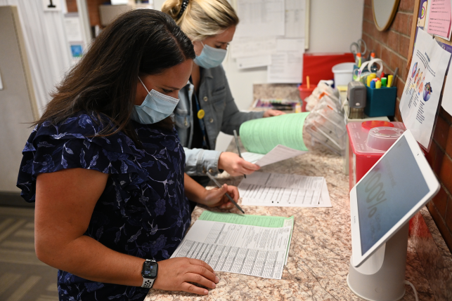 Nurses in mask stare at records