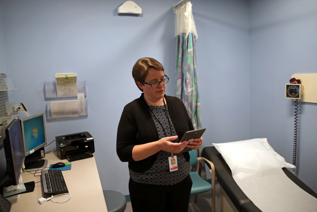 Doctor on ipad in empty exam room