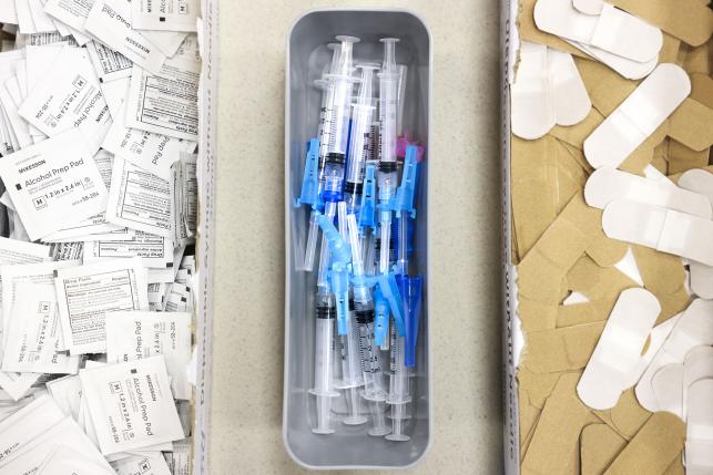 Alcohol swabs, vaccine needles, and bandages on a table