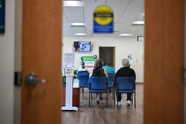 backs of people seen through waiting room door