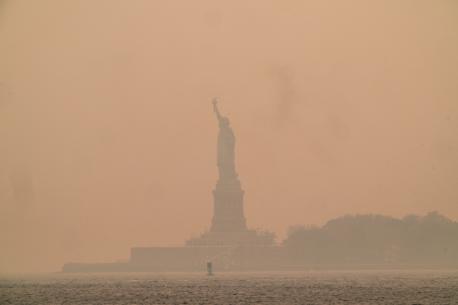 Photo, hazy view of statue of liberty over water.