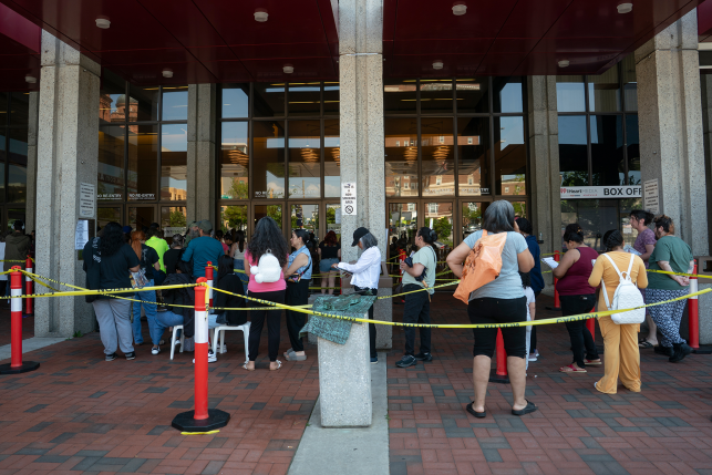 People wait in line in front of building
