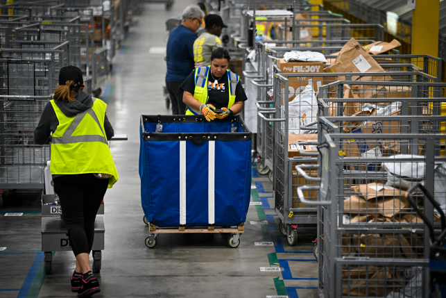 Workers in yellow vests work with packages in warehouse