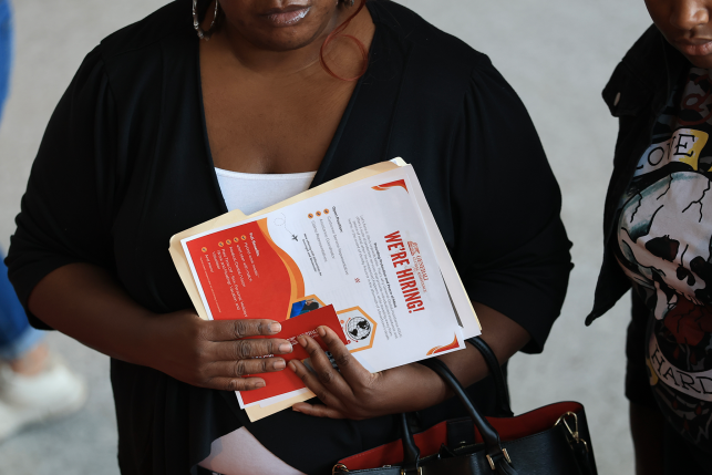 Woman holds up paperwork and folder in front of her chest.