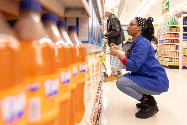 Grocery store employee looks at products in aisle