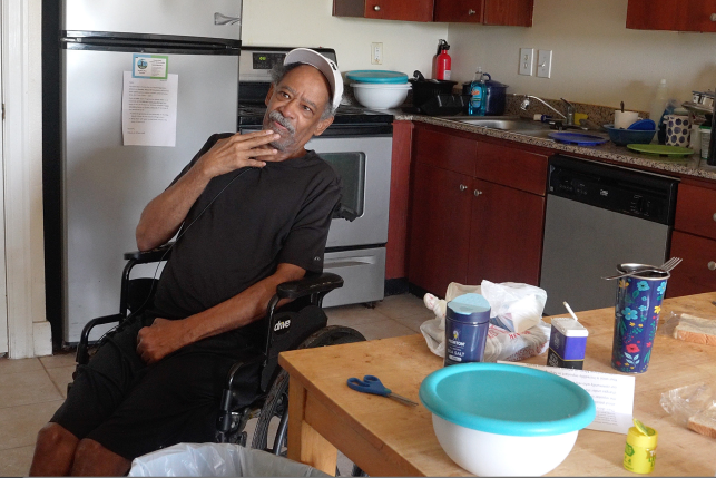 Man in wheelchair sits in his kitchen