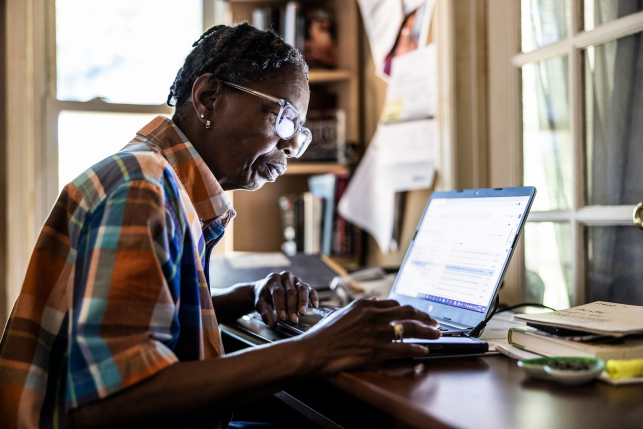 Woman looks at laptop at table