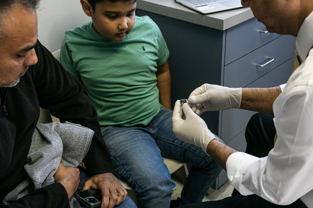 Photo, doctor shows young boy a vaccine