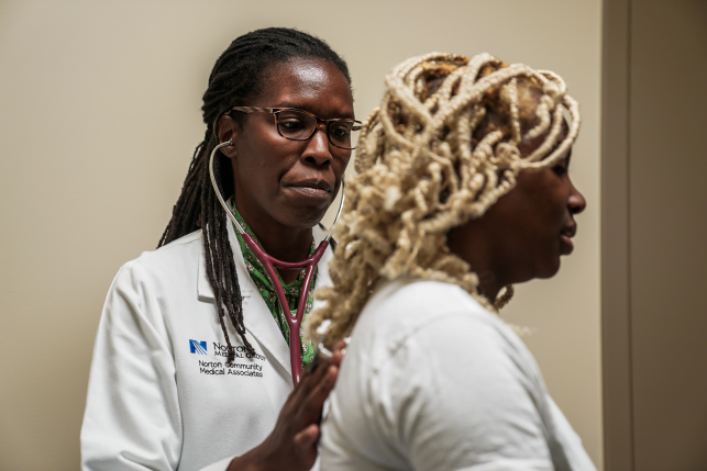 Doctor listens to patient's heart with stethoscope.