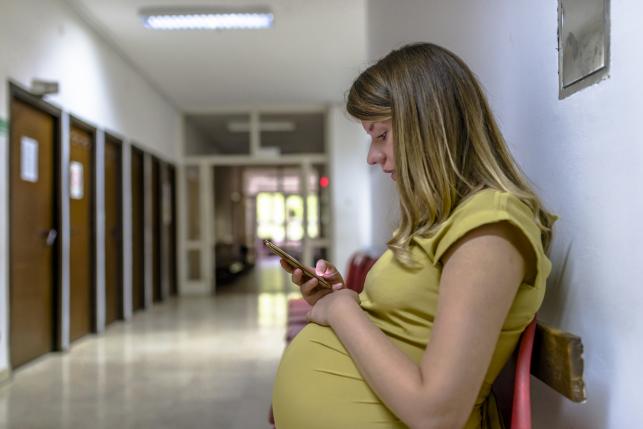 Low-income patient with cell phone in hospital waiting room