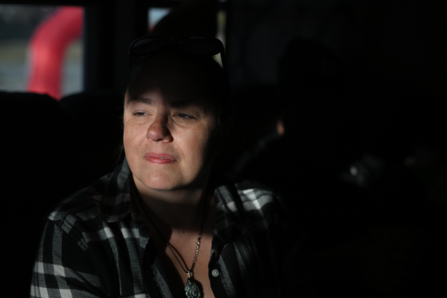Middle-aged woman looks on pensively shrouded in shadows