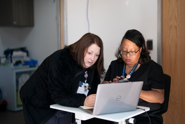two clinic workers look at laptop