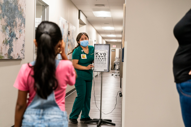 Photo, child takes ey exam in hospital hallway